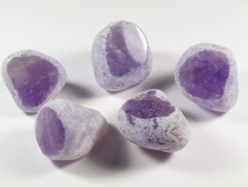 Pięć polerowanych ametystów na białym tle.