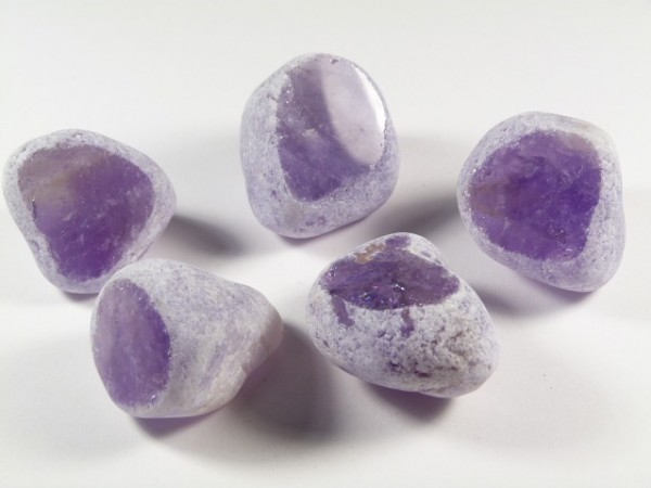 Pięć polerowanych ametystów na białym tle.