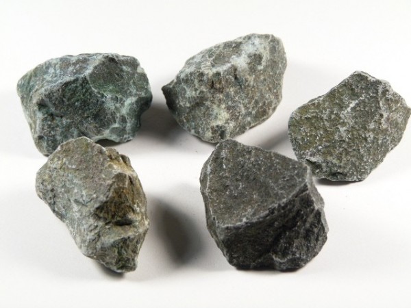 Pięć nieobrobionych, szarych kamieni leży na jasnym tle.