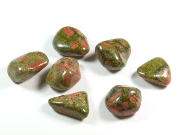 Siedem polerowanych kamieni unakitowych w zielono-różowych odcieniach na białym tle.