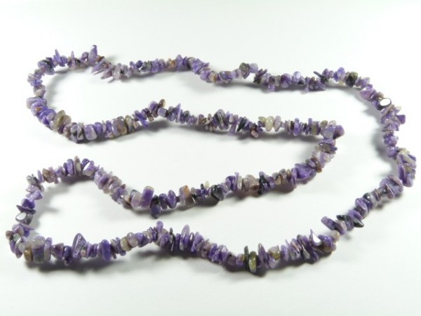 Naszyjnik z drobnych, fioletowych kamieni, ułożony na białym tle.