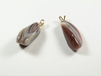 Dwa wisiorki z polerowanego agatu leżące na białym tle.