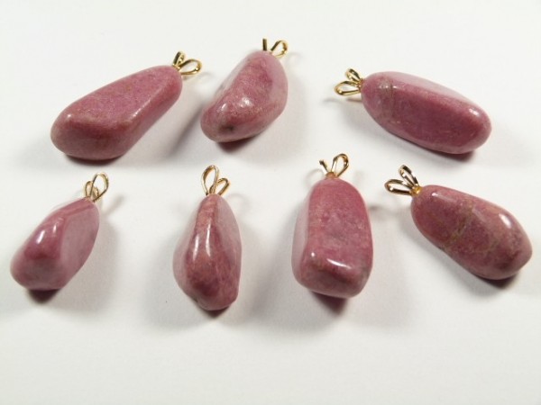 Siedem różowych kamieni z zawieszkami ułożonych na białym tle.