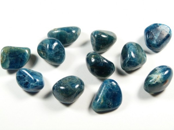 Gładkie, niebieskie kamienie apatytu ułożone na białym tle.