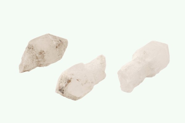 Kwarc sceptre/ kwarc berłowy - kamień naturalny, surowy, nieszlifowany. Trzy białe kryształy kwarcu na jasnym tle.