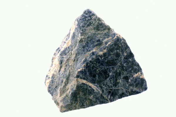 Trójkątny kawałek ciemnego kamienia z jasnymi żyłkami na jasnym tle.