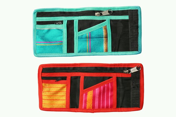 Dwa kolorowe portfele z wieloma kieszonkami i zamkami błyskawicznymi, leżące obok siebie.