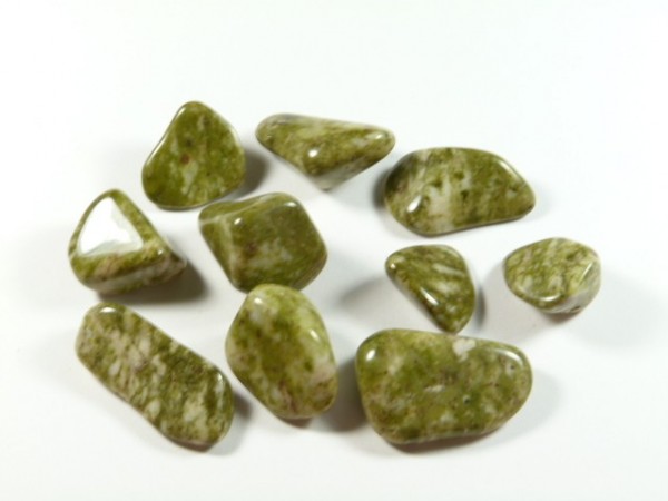 Kilka gładkich, zielonych kamieni leży na białym tle.