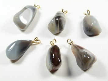 Sześć zawieszek z polerowanych kamieni z agatu, każda z metalowym uchwytem na łańcuszek.
