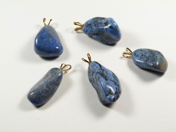 Pięć niebieskich kamieni z zawieszkami do naszyjnika leży na białym tle.