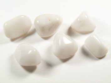 Sześć białych, wygładzonych kamieni leży na białym tle.