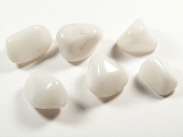 Sześć białych, wygładzonych kamieni leży na białym tle.