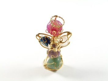 Figurka anioła z koralików i drucików w różnych kolorach na białym tle.