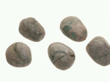 Waryscyt - kamień gładzony, polerowany, szlifowany i bębnowany w formie otoczaka. Pięć gładkich, polerowanych kamieni na jasnym tle.