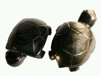 Dwa czarne żółwie z kamienia ustawione obok siebie na jasnym tle.