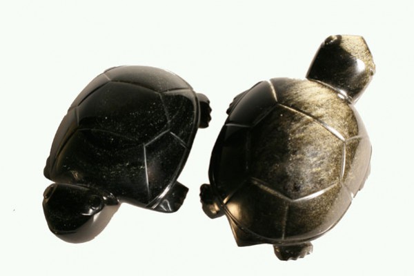 Dwa czarne żółwie z kamienia ustawione obok siebie na jasnym tle.