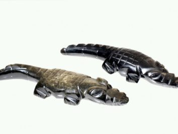 Dwa kamienne krokodyle figurki leżące na białym tle.