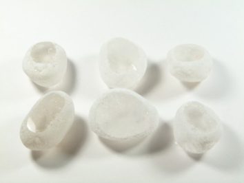 Sześć nieregularnych bryłek lodu na białym tle.