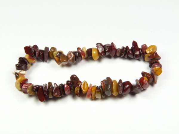 Bransoletka z kolorowych, nieregularnych kamieni na białym tle.