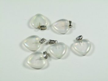 Sześć przezroczystych wisiorków w kształcie serca leży na białym tle.