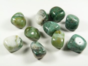Jadeit afrykański - kamień gładzony, polerowany, szlifowany i bębnowany w formie otoczaka. Polerowane zielone kamienie jadeitu leżące na białym tle.