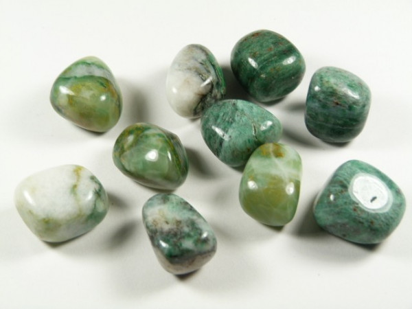 Jadeit afrykański - kamień gładzony, polerowany, szlifowany i bębnowany w formie otoczaka. Polerowane zielone kamienie jadeitu leżące na białym tle.