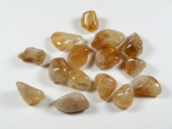 Kilka oszlifowanych, brązowo-żółtych kamieni leży na białym tle.
