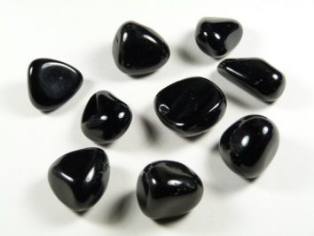 Obsydian czarny - kamień gładzony, polerowany, szlifowany i bębnowany w formie otoczaka. Dziewięć czarnych, gładkich kamieni leży na białym tle.