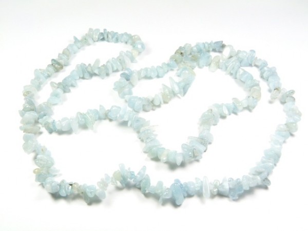 Naszyjnik z drobnych, nieregularnych, jasnoniebieskich kamieni na białym tle.