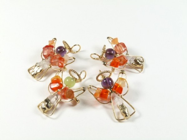 Cztery ozdoby w kształcie aniołów wykonane z kolorowych koralików na białym tle.