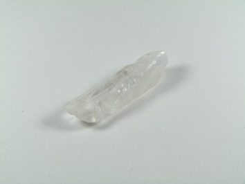 Przezroczysty kryształ kwarcu leżący na białym tle.