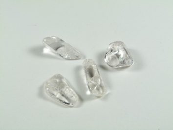 Cztery przezroczyste kryształki leżące na białym tle.