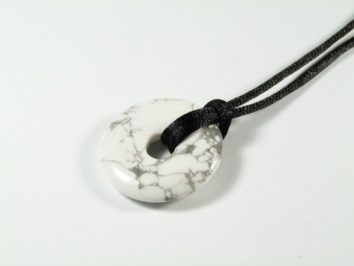 Biały okrągły wisiorek z czarnym sznurkiem, wykonany z kamienia z szarymi żyłkami.