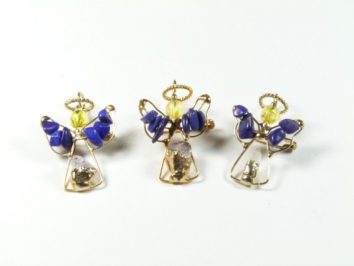 Trzy figurki aniołów z drutu i koralików na białym tle.