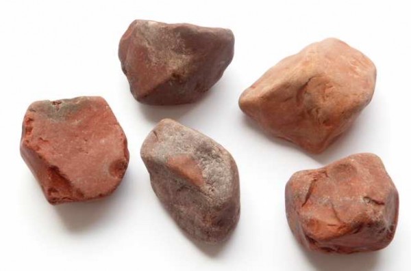 Bloodstone/ krwawnik/ heliotrop - kamień surowy, naturalny, nieszlifowany. Pięć nieregularnych, czerwonych kamieni leży na białym tle.