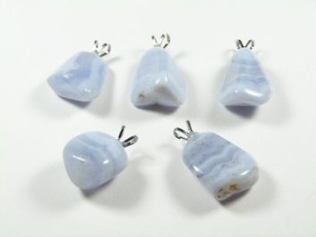 Pięć niebieskich wisiorków z kamieniami leży na białym tle.