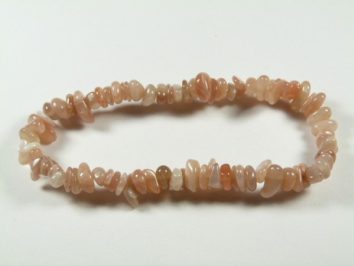 Bransoletka z różowych kamieni na elastycznej żyłce, ułożona na białym tle.