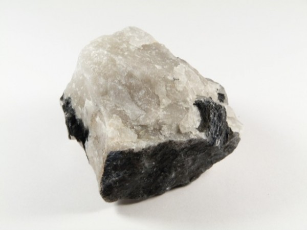 Skała biało-czarna o szorstkiej powierzchni na białym tle.