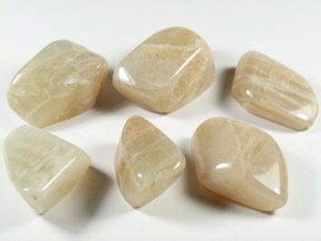 Sześć gładkich, polerowanych kamieni księżycowych na białym tle.