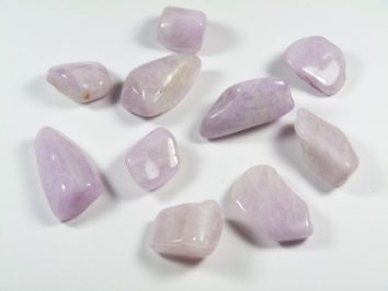 Jasnoróżowe, oszlifowane kamienie leżące na białym tle.