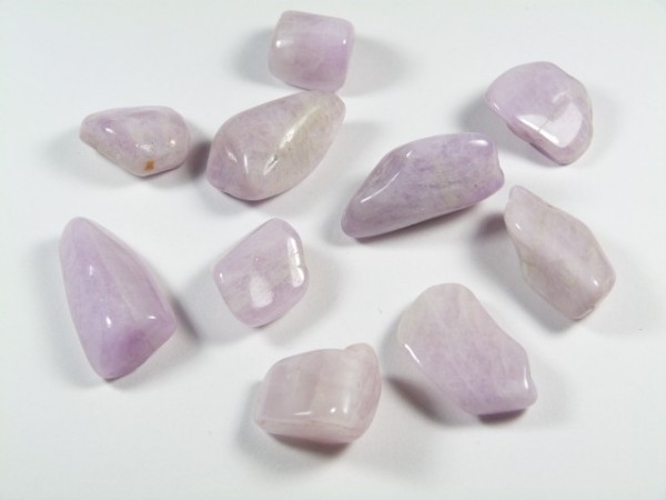 Jasnoróżowe, oszlifowane kamienie leżące na białym tle.