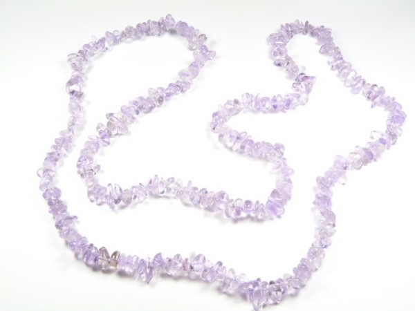 Naszyjnik z fioletowych, nieregularnych koralików z kamieni szlachetnych na białym tle.