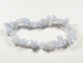 Bransoletka z niebieskich, nieregularnych kamieni na białym tle.