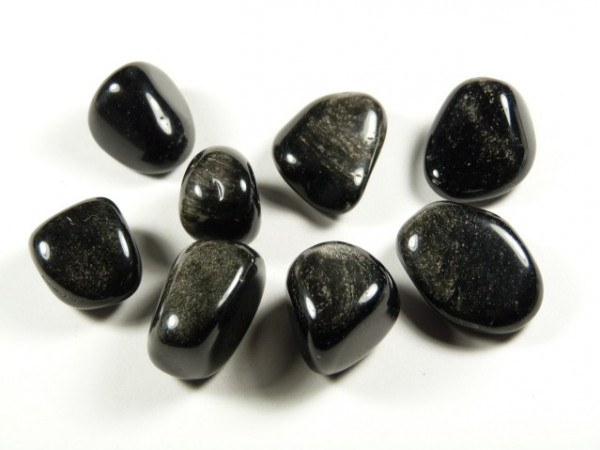 Obsydian srebrny - kamień gładzony, polerowany, szlifowany i bębnowany w formie otoczaka. Osiem wypolerowanych, czarnych kamieni leży na białym tle.