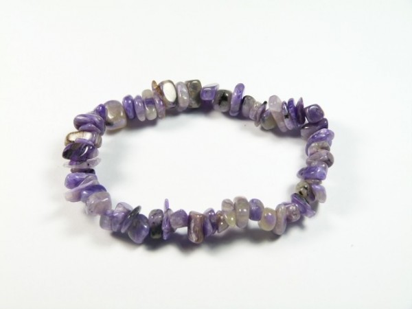 Bransoletka z nieregularnych, fioletowych kamieni na białym tle.