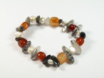 Bransoletka z kolorowych kamieni i pereł na białym tle.