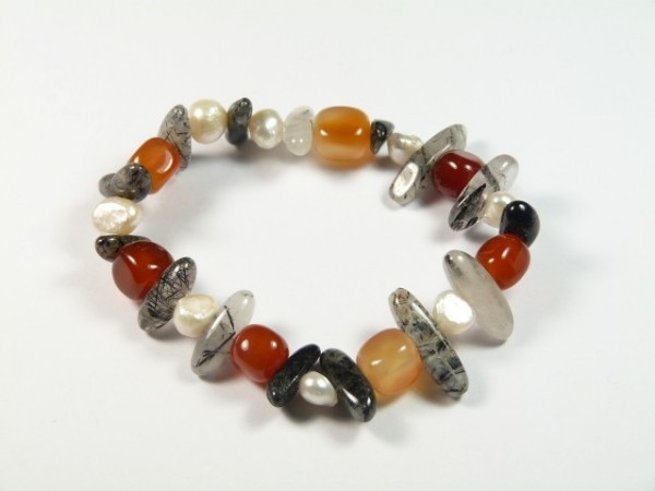 Bransoletka z kolorowych kamieni i pereł na białym tle.