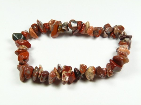 Bransoletka z nieregularnych, czerwono-brązowych kamieni na białym tle.