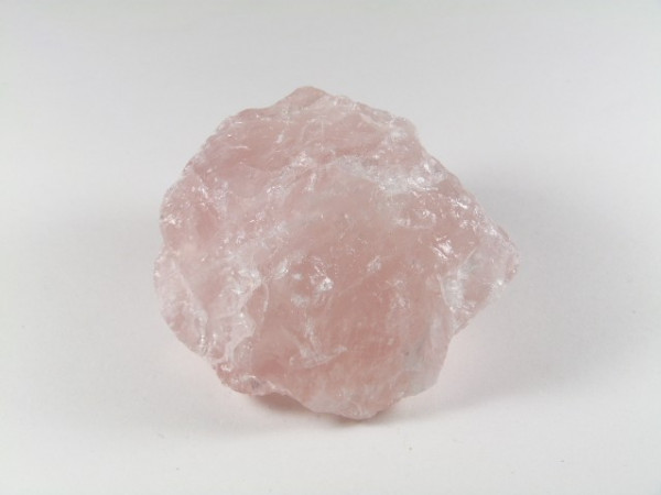 Różowy, surowy kryształ kwarcu na białym tle.