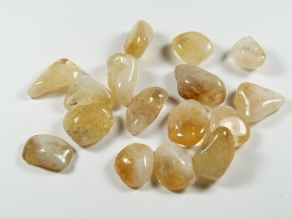 Kilka polerowanych, żółtych kamieni leży na białym tle.